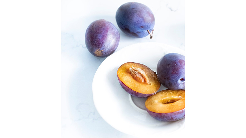 Plums on and around a white plate