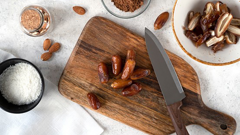 Dates on wooden cutting board with other ingredients around